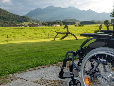 Barrierefreier Urlaub auf dem Bauernhof. Rollstuhl vor Bergpanorama